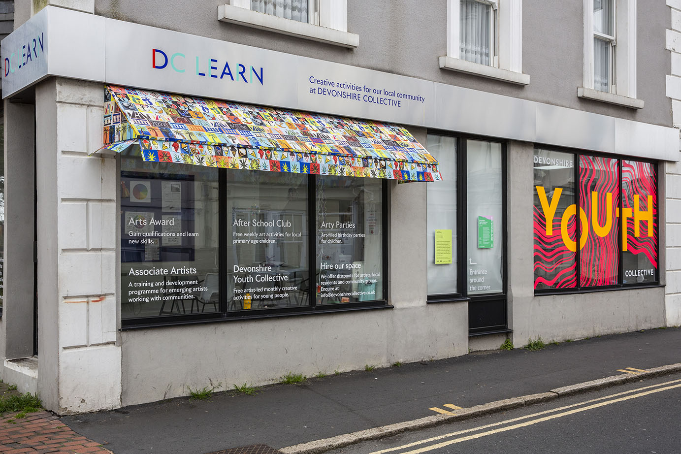 DC Learn with an awning made from colourful fabric. The fabric design is made up of tiles with symbols including palm trees, moons, sun and ice cream. 