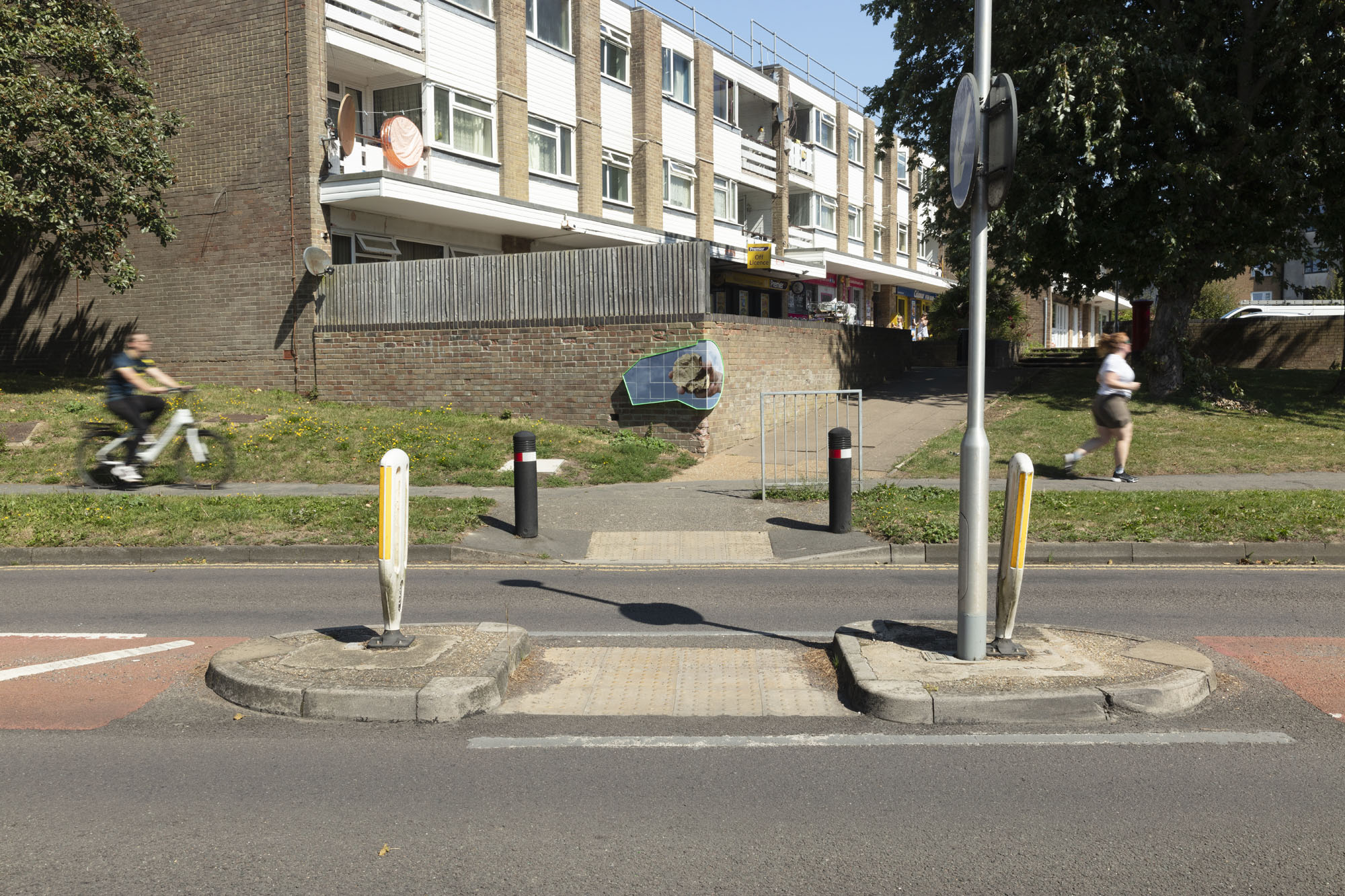 Tiles printed with a photograph of a hand holding a bronze cast object are installed on a wall by Pembury Road Shops