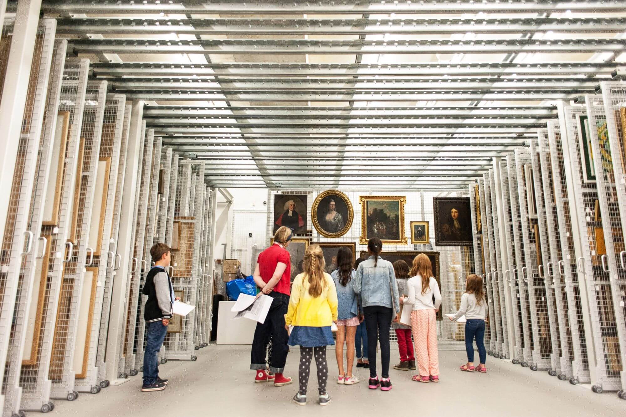A group of young people in Towner's Art Store, looking at paintings hanging on a metal rack
